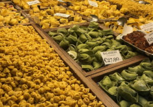 An Italian streetside market features various types of pasta and food. 